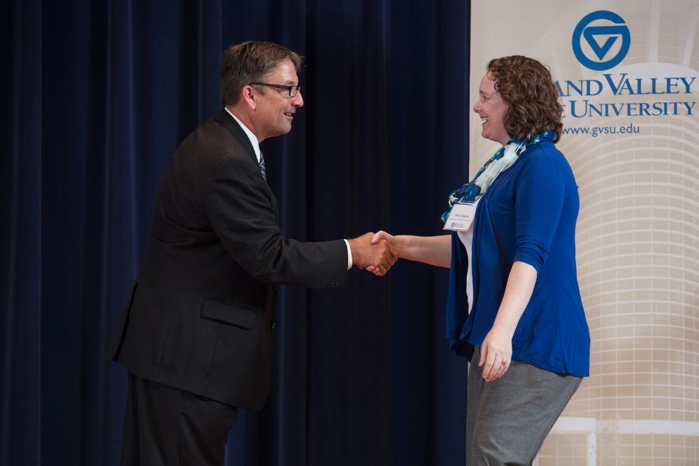 Doctor Smart shaking hands with an award recipient in a blue cardigan